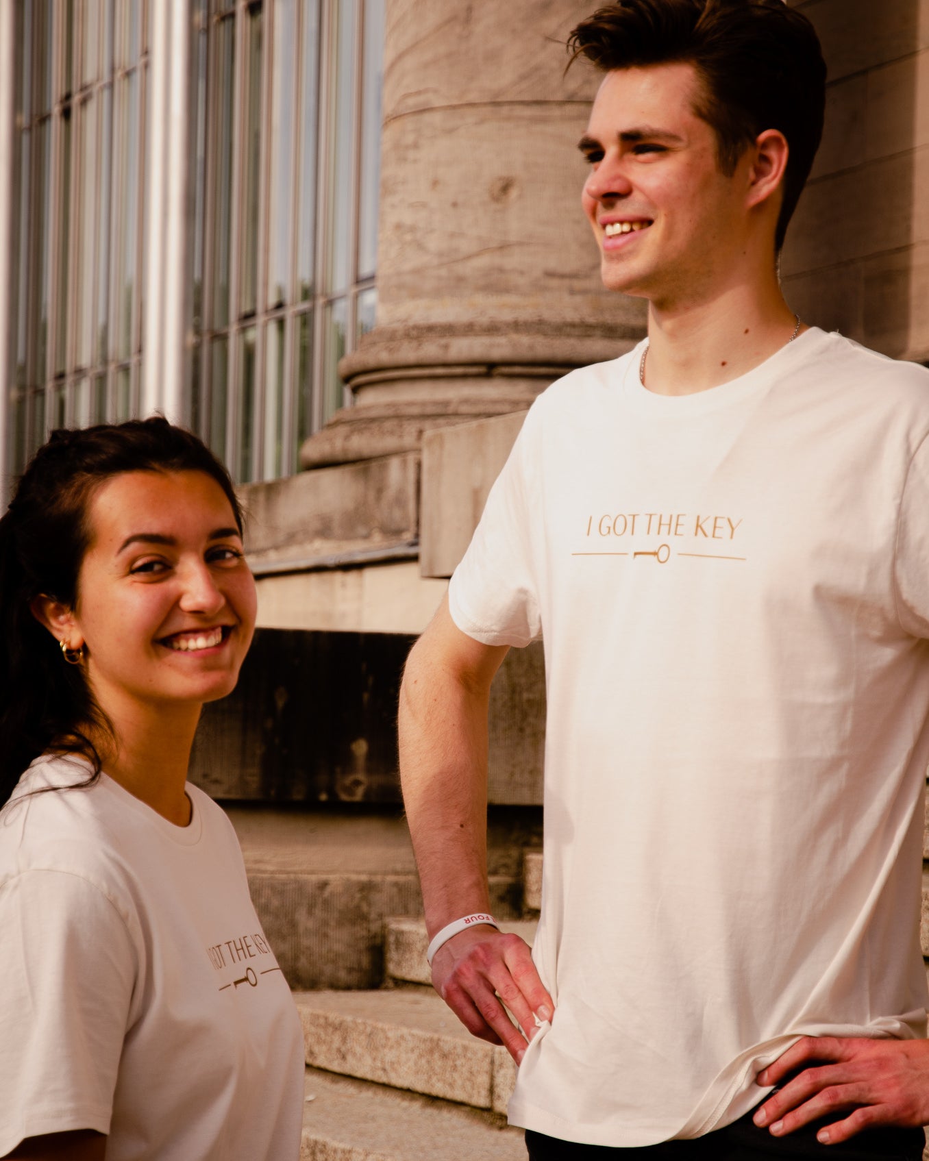 Frau und Mann tragen beide ein cremeweißes T-Shirt mit goldenem I GOT THE KEY Druck