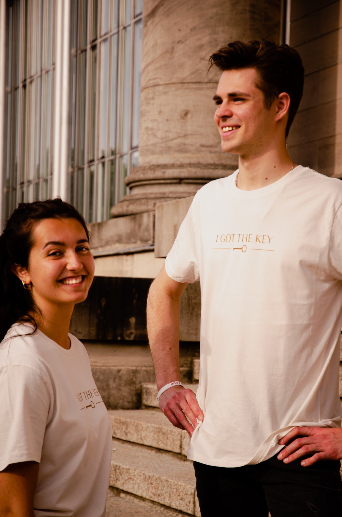 Frau und Mann tragen beide ein cremeweißes T-Shirt mit goldenem I GOT THE KEY Druck